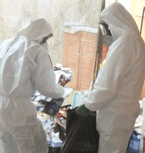 Tatortreinigung mit zwei Männer in Aspestschutzanzügen bei der Arbeit